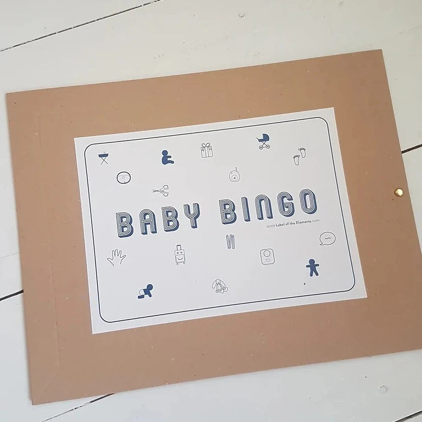 Bruine enveloppe van Baby Mijlpalen Bingo met wit etiket en blauwe pictogrammen op een witte houten ondergrond.