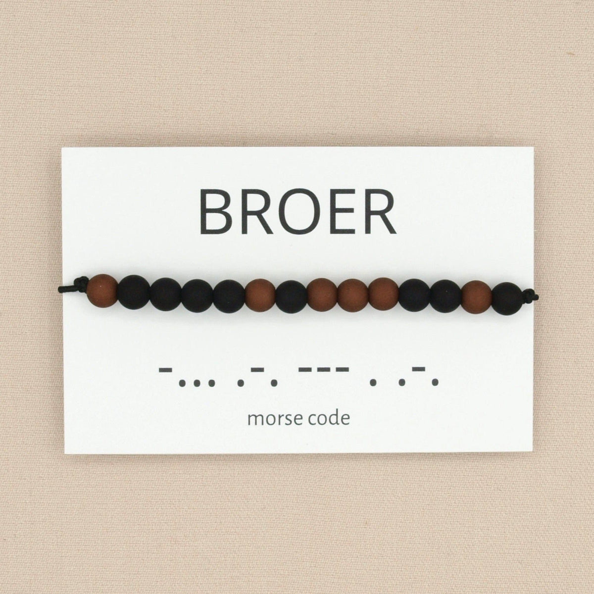 Morsecode-armband voor broer met zwarte en bruine kralen op een wit kaartje met ‘broer’ en de bijbehorende morsecode.