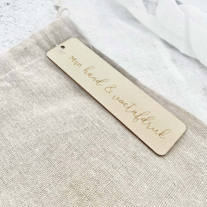 Detail van het label ‘Mijn hand & voetafdruk’ op het beige linnen bewaarzakje.