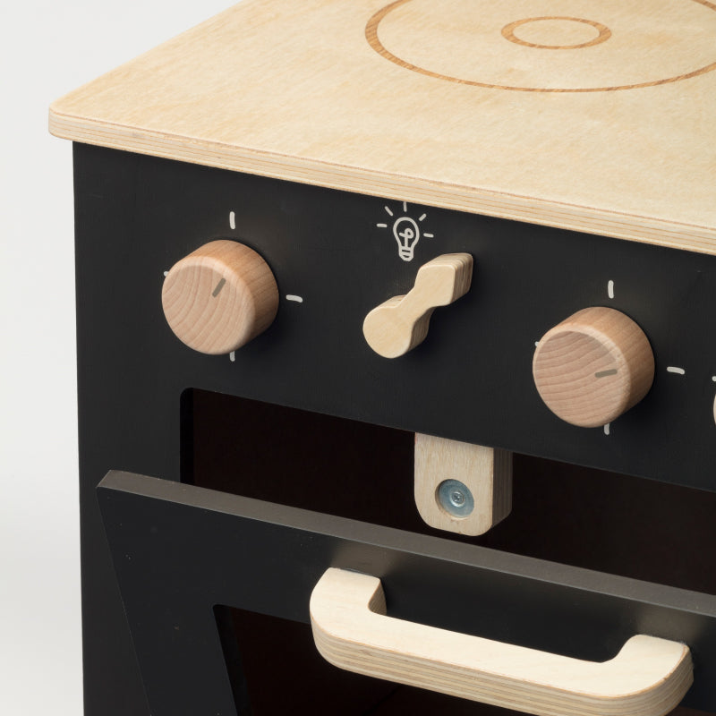Detail van de zwarte houten speelkeuken met houten knoppen en een geopende ovendeur met houten handgreep.