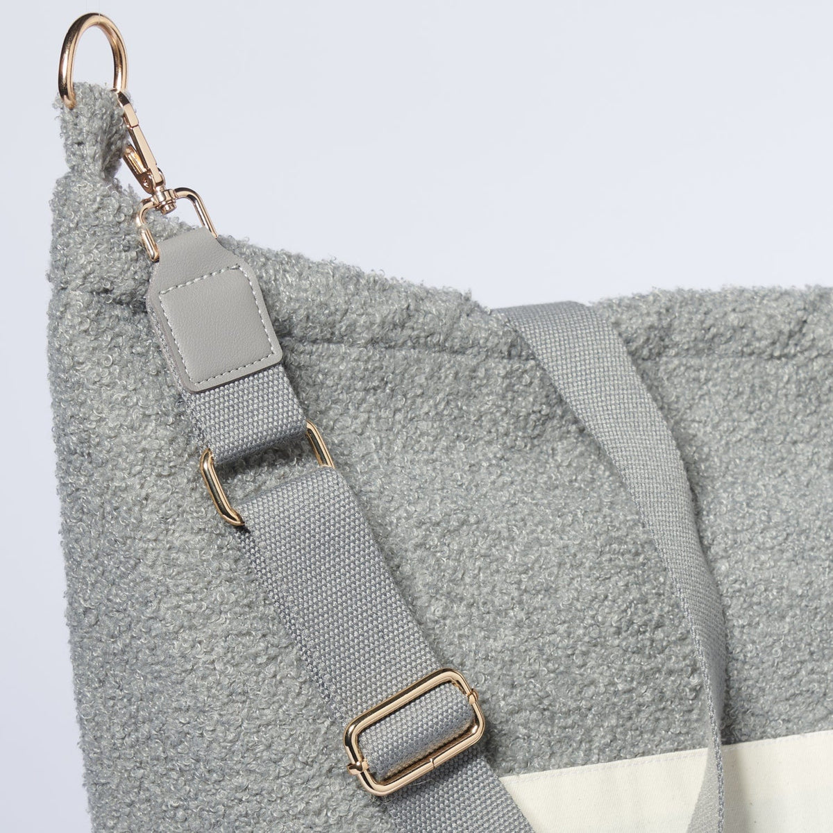 Detail van de grijze Mom Bag Teddy Bouclé met verstelbare schouderriem en goudkleurige karabijnhaak.