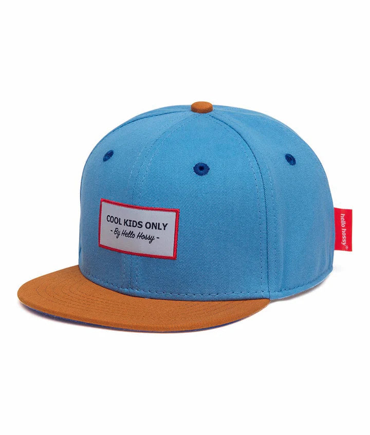 Hello Hossy Mini Jean pet in blauw met een bruine klep en een rechthoekig label op de voorkant.