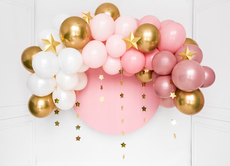 Roze, witte en gouden ballonnenboog rond een roze cirkel, versierd met gouden sterren en sterrenslingers