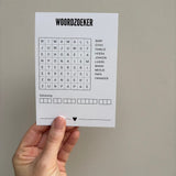 Hand houdt een witte A6-woordzoekerkaart om een peter te vragen tegen een neutrale achtergrond.