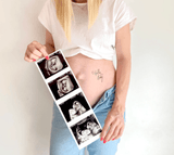 Zwangere vrouw met zwarte Hello Baby-plaktattoo op haar buik en een strook echobeelden in haar handen.