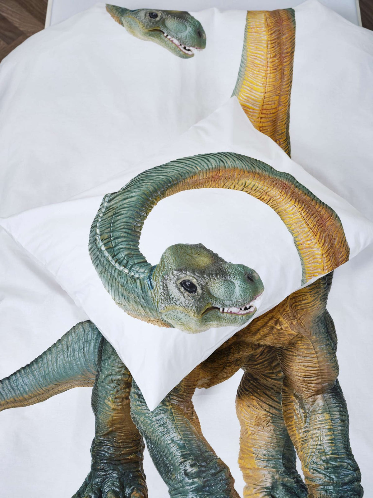 Detail van het witte Dino Bronto dekbedovertrek en kussensloop met een groen-gele dinosaurus met lange nek.