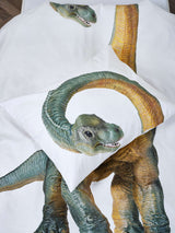Detail van het witte Dino Bronto dekbedovertrek en kussensloop met een groen-gele dinosaurus met lange nek.