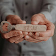 Flesopener met beukenhouten handvat en gravure ‘Best Dad!’, vastgehouden in twee handen.