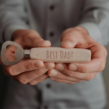 Flesopener met beukenhouten handvat en gravure ‘Best Dad!’, vastgehouden in twee handen.