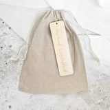 Gesloten beige linnen bewaarzakje met trekkoord en label ‘Mijn hand & voetafdruk’.