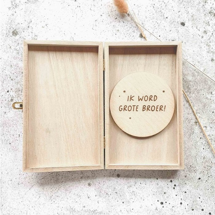 Open houten kistje met een houten cirkel met de tekst ‘Ik word grote broer!’ op een lichtgrijze ondergrond.