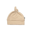 Donkerbeige knoopmutsje met wafelstructuur, omgeslagen rand en een knoop bovenop, op een witte achtergrond.