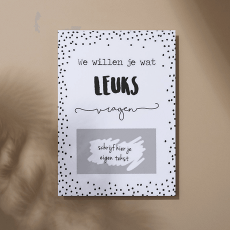 Witte kraskaart met zwarte stippen, de tekst ‘We willen je wat leuks vragen’ en een grijs vak voor je eigen tekst.