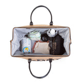 Open Mommy Bag verzorgingstas van bovenaf, met grijze binnenkant, luiers, kleertjes en een fles in de vakken.
