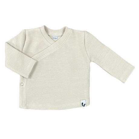 Beige overslagshirtje in ribstof met lange mouwen en een drukknoop aan de zijkant.