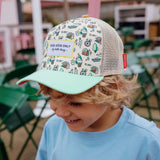 Kind met de Hello Hossy Adventure pet met kleurrijke illustraties, mintgroene klep en beige mesh achterkant.
