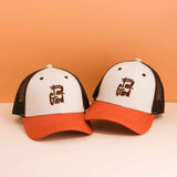 Twee Feel Good-petten met off-white voorkant, bruin borduursel en roestkleurige klep tegen een oranje achtergrond.