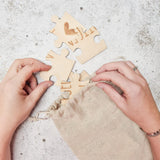Handen halen houten stukjes van de puzzel ‘Wij krijgen een baby’ uit een beige linnen zakje.