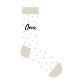 Witte sok met beige stippen, boord, hiel en teen en het zwarte opschrift ‘Oma’.