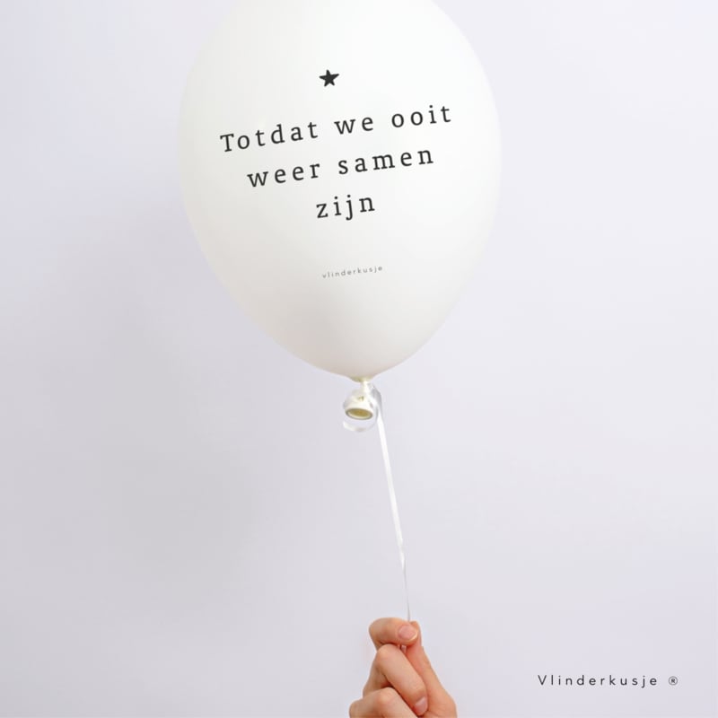 Witte troostballon met zwart sterretje en de tekst ‘Totdat we ooit weer samen zijn’, aan een lint vastgehouden.