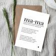 Witte A6-ansichtkaart met zwarte tekst over mama en een hartje, op een bruine envelop naast groene takjes.