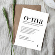 Witte ansichtkaart Oma met zwarte tekst en een hartje, op een bruine envelop naast groene takjes.