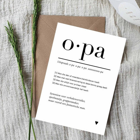 Witte A6 ansichtkaart voor opa met zwarte tekst en hartje, op een bruine envelop tussen groene takjes.