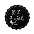 Zwarte ronde sticker met geschulpte rand, witte tekst ‘it's a girl’ en een klein bloemetje.