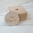 Ronde houten badge met ‘Je wordt papa’ en een hartje, voor een gesloten houten kistje met hartje op het deksel.