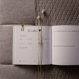 Open zwangerschapsdagboek op grijze stof, met invulpagina’s voor 32 weken en droogbloemen.