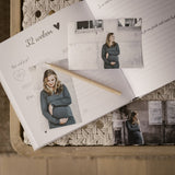 Open zwangerschapsdagboek bij 32 weken, met foto’s van een zwangere vrouw en een potlood.