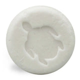 Witte, ronde Shampoo Bar Baby met een schildpadmotief, tegen een witte achtergrond.