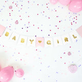 Baby Girl-slinger met witte en roze vlaggetjes, gouden letters en een hartje, tussen roze ballonnen en confetti.