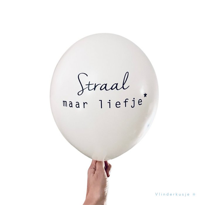 Witte troostballon met de zwarte tekst 'Straal maar liefje' en een sterretje, vastgehouden door een hand.