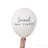 Witte troostballon met de zwarte tekst 'Straal maar liefje' en een sterretje, vastgehouden door een hand.