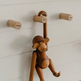Drie houten Family-wandhaken aan een witte wand, met een houten aap aan de haak met opschrift Papa.